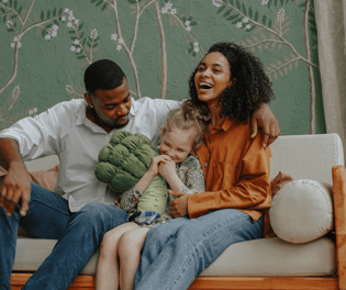 two adults embracing child on sofa